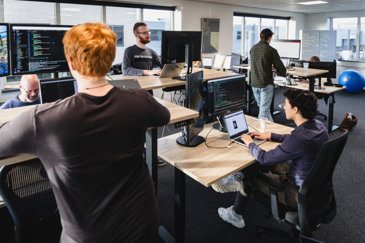 A group of SUE engineers working behind their computers. Screens have lines with code.