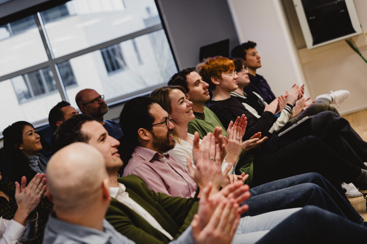 A group of people sitting in an office and clapping.