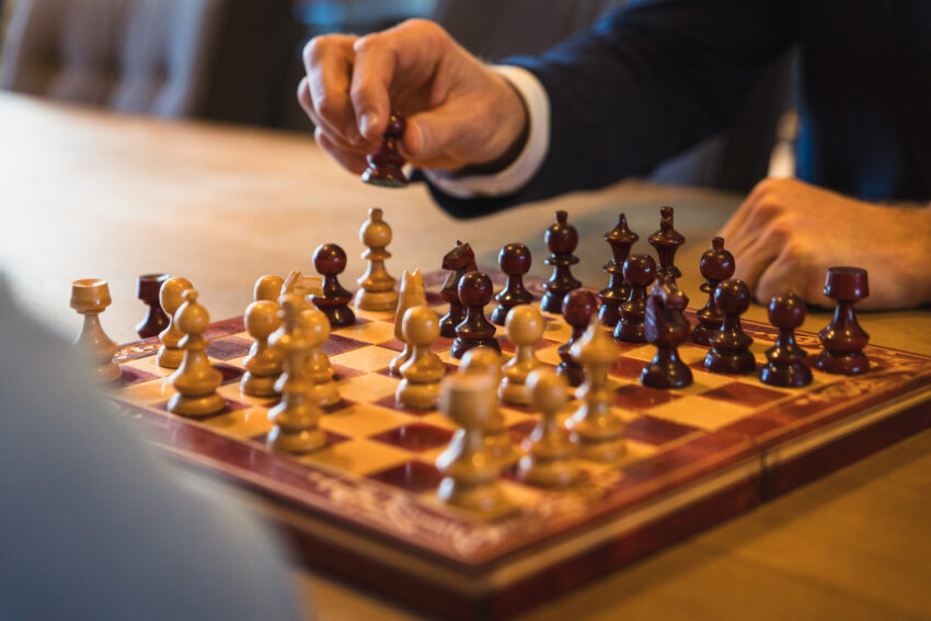 Chessboard, with a hand above it.