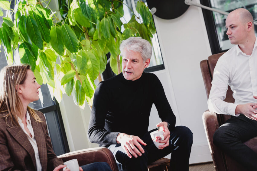 Three people sitting in front of a plant.