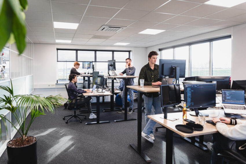 Multiple people in a room behind desks, working on computers