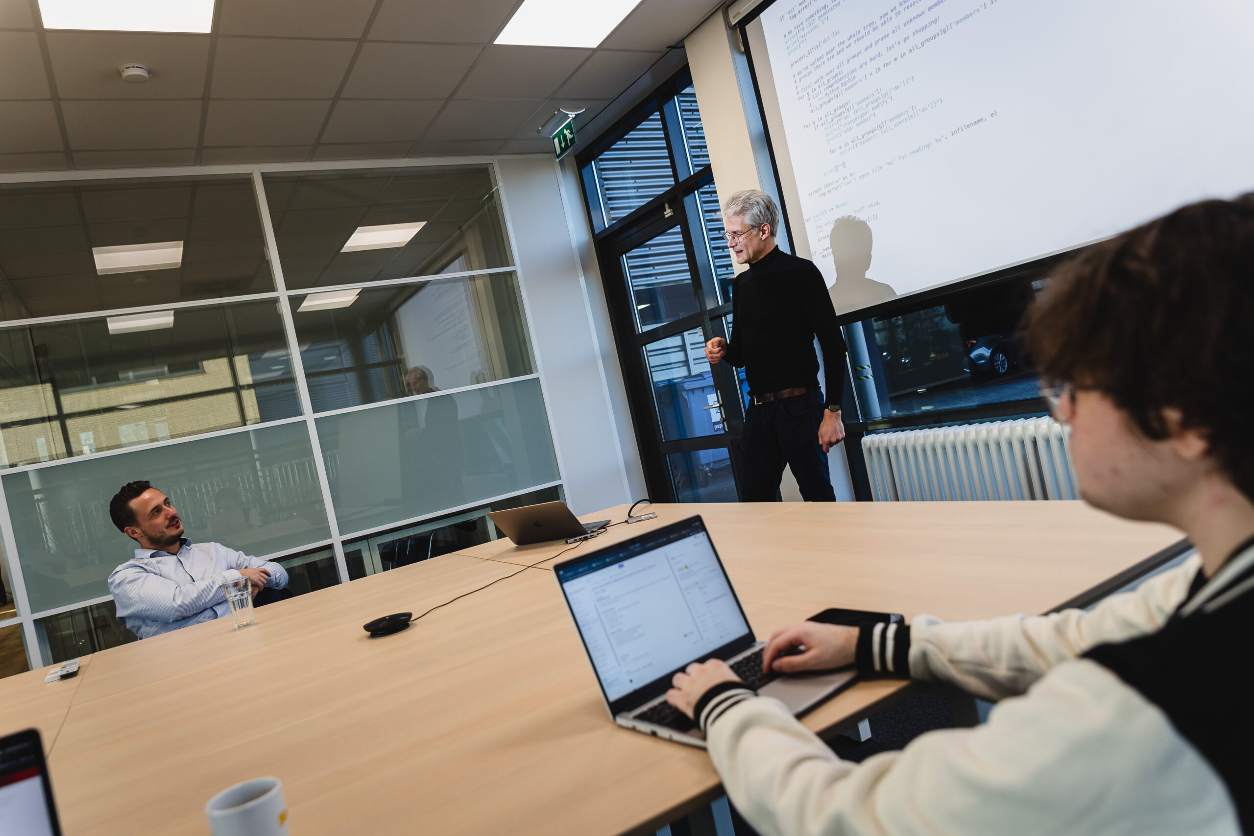 People in a meeting room. One person presenting.