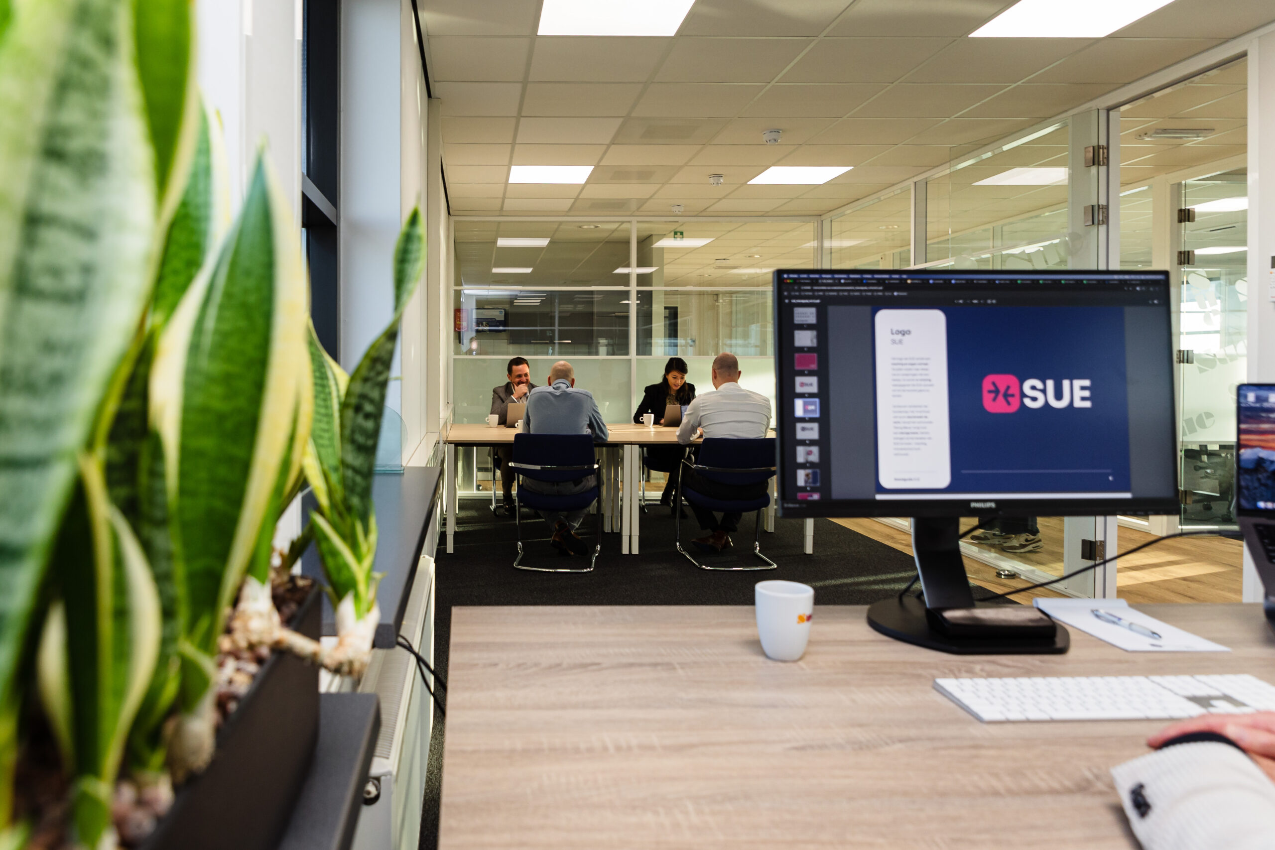 Computer with SUE and plants with people in the background