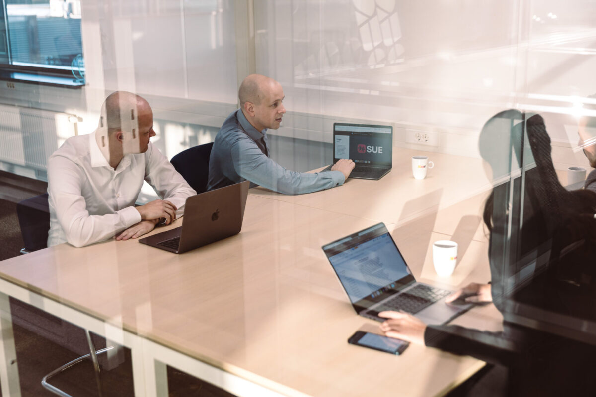 People in a meeting, around a table with laptops.