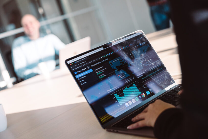 A laptop screen with Multistax on it. A person in the back.